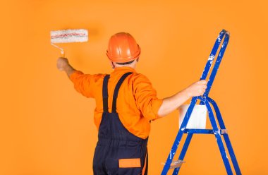 Foreman müfettişi. Kıdemli boyacı merdivende paten kullanır. Duvarı sarıya boyamak. İş kıyafetleri içinde profesyonel bir ressam. Odada duvar boyama işçisi. Tekerlekli erkek dekoratör.