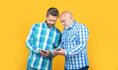 Nesiller boyunca erkekler arka planda telefon kullanır. Erkeklerin telefon kullandığı neslin fotoğrafı. Nesiller boyu erkekler sarıda izole telefon kullanır. Nesiller boyu erkekler stüdyoda telefon kullanır..