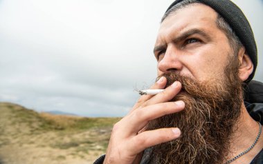 Sigara içen sakallı adam, uzay afişini kopyala. Sigara içen sakallı adam. Dağda sigara içen bir adamın fotoğrafı. Sigara içen bir adam..