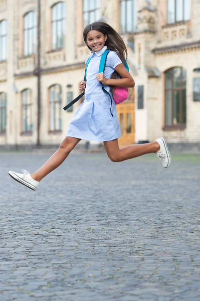 快乐地跳着学校的黑发女孩 背着背包跳上学的女孩 在户外跳着上学的女孩 跳楼女生的照片 — 图库照片