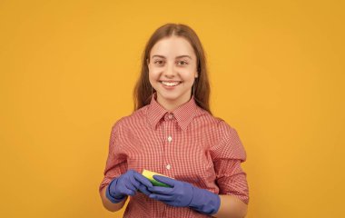 happy child in rubber gloves with sponge on yellow background.