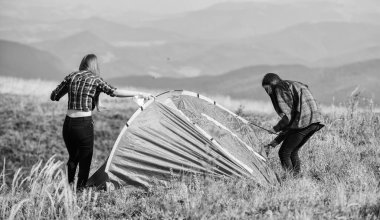 Dağlarda tatil. Kamp gezisi. Çadır kuracak bir ortağın olması ne güzel. Kızlar dağın tepesine çadır kurdular. Kamp becerileri konsepti. Kamp ve yürüyüş. Hiçliğin ortasında. Geçici konut.