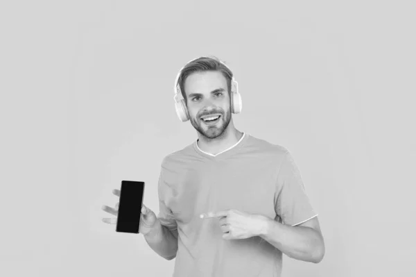Happy Young Man Listening Music Headphones Pointing Finger Mobile Phone — Fotografia de Stock