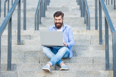 Mutlu adamın dışarıda online video iletişimi var. Adamın dışarıda çevrimiçi video bağlantısı var. Adamın merdivenlerde online video bağlantısı var. Adamın dizüstü bilgisayarında video bağlantısı var..