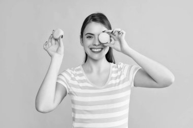 glad girl with macaron on yellow background.