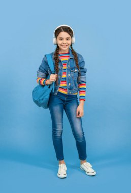 Mutlu genç kız kulaklıkla müzik dinliyor mavi arka plan, eğitim. Okul eğitimi. Resmi olmayan eğitim.
