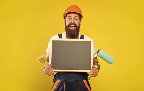 Glücklicher Mann Maler Helm Und Arbeitskleidung Halten Farbroller Und Tafel — Stockfoto