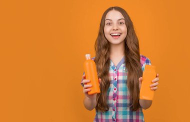 şaşırmış çocuk sarı arka planda şampuan şişesi ile.