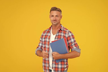 Okul kitaplarını elinde tutan mutlu adam sarı arka plan, eğitim.