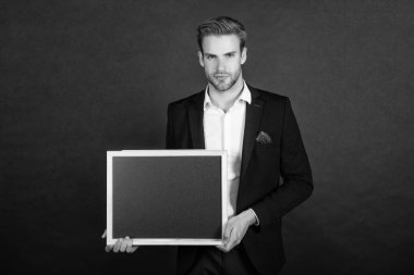 Resmi takım elbiseli ciddi bir adam elinde boş bir karatahta fotokopi odası koyu arkaplan, öğretmen.