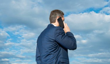 Bir adamın arkadan görünüşü telefon konuşması giysisi gibidir. Adamın fotoğrafı telefonda konuşuluyor. Adamın gökyüzü geçmişinde telefon konuşmaları var. Adamın dışarıda telefon konuşması var..