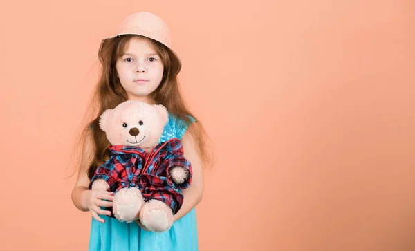 Cutest ever. Small girl straw hat hold teddy bear plush toy. In love with cute teddy bear. Happy childhood. Tender attachments. Kid little girl carefully hug soft toy teddy bear beige background.