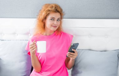 Kahveli kadın telefonda konuşuyor. Kadın telefonuyla evde sohbet ediyor. Kadının evinde telefon görüşmesi..