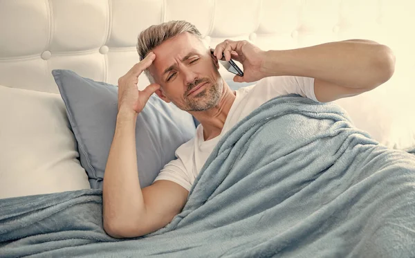 Confused Mature Man Bed Speaking Phone — 图库照片