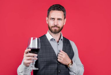 Resmi olarak yakışıklı adam içmek için kırmızı şarap bardağı taşıyor, şerefe..