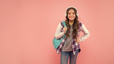 Çocukluk gelişimi. Modern kulaklıklı, sırt çantalı bir çocuk. Online eğitim. Okula dönüyorum. Kulaklıklı mutlu genç kız. Müzik dinle. kopyalama alanı. yeni teknoloji.