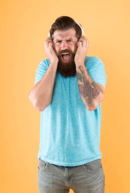 Hipster kırık kulaklık müzik gadget dinleyin. Nefret dolu bir şarkı. Müzik tadı. Sakallı adam müzikten hoşlanmaz. Rahatsız edici bir ses. Müzik kablosuz kulaklık dinleyen adam. Ekolayzır ayarları. Korkunç ses.