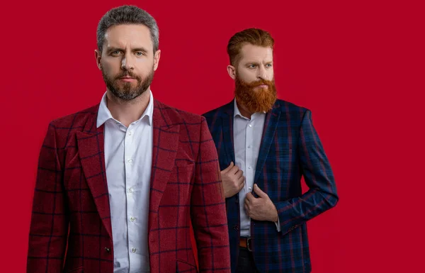 selective focus of formal elegant men on background. photo of formal elegant men in formalwear. formal elegant men isolated on red. formal elegant men at studio.