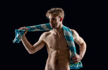 Stüdyoda kaslı bir adam var. Gövdesinde havlu tutan kaslı bir adam. Adamın kaslı gövdesinin fotoğrafı. Gövdesinde havlu olan kaslı adam siyah arka planda izole edilmiş..