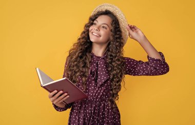 glad child with frizz hair read book on yellow background.