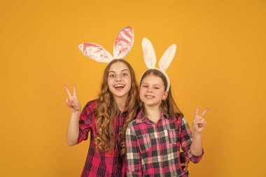Sarı arka planda tavşan kulaklı mutlu Paskalya çocukları. Barış.