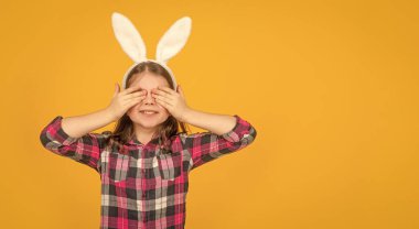 Tavşan kulaklı mutlu Paskalya çocuğu sarı arka planda fotokopi alanı ile.
