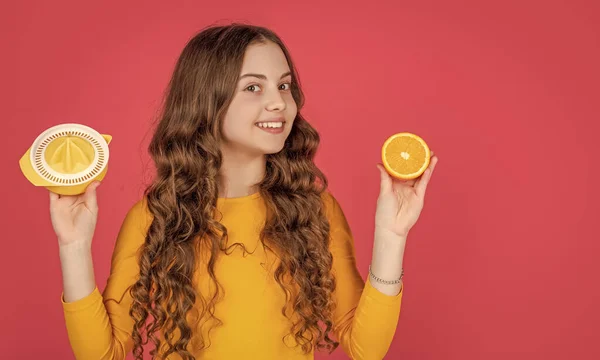 stock image happy teen kid hold orange and juicer on pink background.