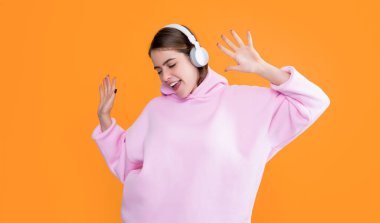 Neşeli genç kız sarı arka planda kulaklıkla müzik dinliyor..