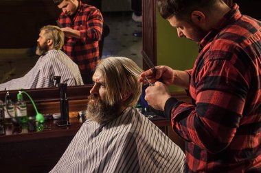 Berber berber dükkanı. Hippi saç tıraşı oluyor. Profesyonel kozmetik. Makas kesme. Saçları boyalı adam. Kısa saç her zaman uzun saçtan daha az iş değildir. Bağış ve yardım konsepti.