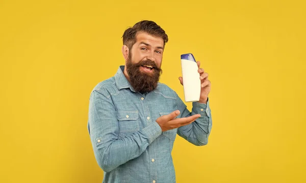 Uomo Barbuto Sorridente Brutale Presentando Bottiglia Condizionatore Capelli Sfondo Giallo — Foto Stock