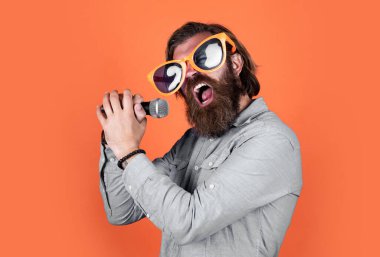 sing to the rhythm of your heart. concept of music. performer having fun. mature bearded man in funny party glasses sing song. brutal male hipster with microphone. vocal school. favorite music style. clipart