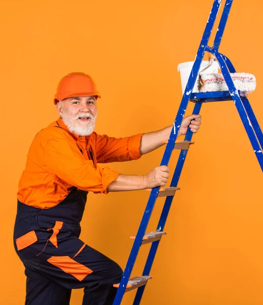 Painter man staircase. To make repairs. man in working clothes painting wall in empty room. painter in overall and cap with paint bucket. builder worker painting facade. thermal insulation works.
