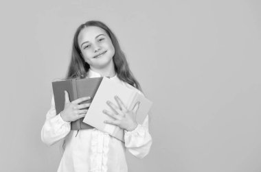 Neşeli çocuk, sarı arkaplanlı, fotokopi ve eğitim alan okul kitabını tutuyor..