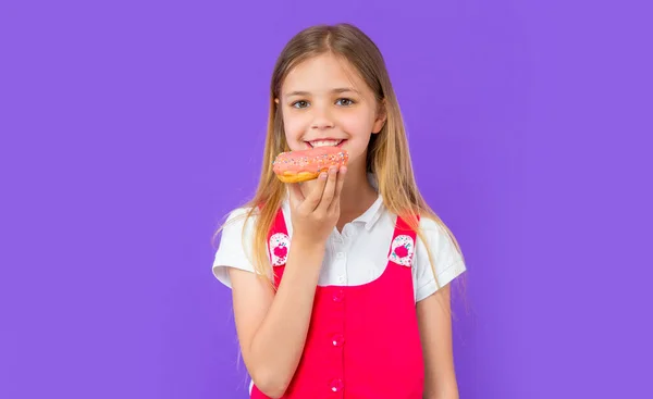 stock image photo of teen girl eat yummy donut. teen girl with yummy donut isolated on purple. teen girl with yummy donut in studio. teen girl with yummy donut on background.