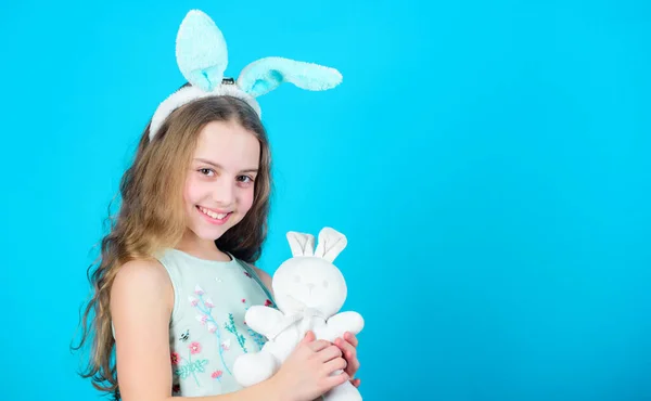 I love Easter. Little child in Easter rabbit style playing with toy. Small kid with cute toy. Easter bunny rabbit. Little girl and rabbit toy. Small baby in rabbit ears with Easter toy, copy space.