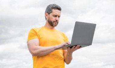 Bilgisayarda çalışan bir adam gökyüzü arka planında. iş çevrimiçi.