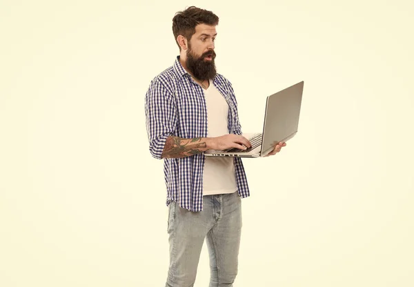In trendy hipster style. Hipster working on computer. Bearded hipster holding with modern laptop in hands. Brutal caucasian hipster using new computing technologies.