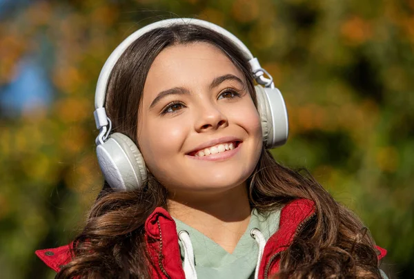 音楽を聴いている10代の少女の顔写真です 10代の女の子が屋外で音楽を聴いて 外で音楽を聴いてる10代の女の子 十代の女の子はヘッドフォンを着て音楽を聞く — ストック写真
