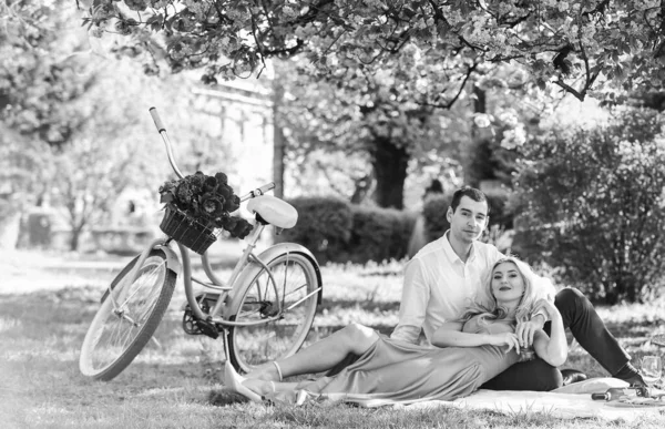 Arrived by bike. Long lasting relationship. Couple having picnic in park. Blooming garden. Perfect spring date. Man and woman in love. Couple sit blanket. Happy together. Romantic picnic. Picnic time.