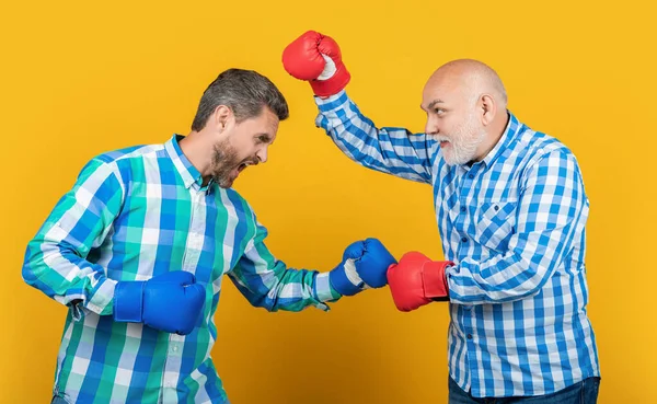 黄色で隔離された2世代の男を怒らせた スタジオで戦う世代の男だ 背景で戦う世代の男たち 世代の男性の戦いの写真ボクシングの手袋を着用 — ストック写真