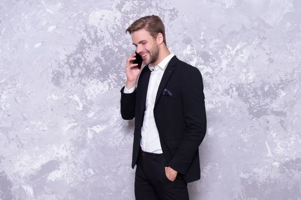 happy business man talk on phone in studio. business man talk on background. photo of business man talk on phone wear suit. successful business man talk on phone isolated on grey.