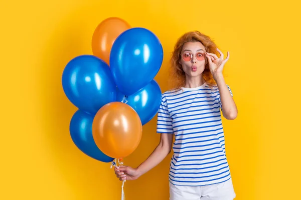 cheerful woman with birthday balloon in sunglasses. happy birthday woman hold party balloons in studio. woman with balloon for birthday party isolated on yellow background.