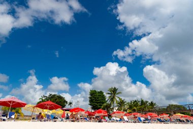 Bridgetown, Barbados - 12 Aralık 2015: Yaz tatilinde plajda insanlarla birlikte güverte sandalyesi.