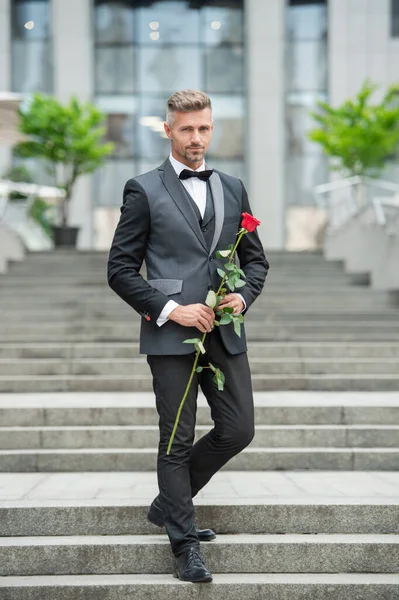 爱日的概念 穿着燕尾服的男人带着爱的玫瑰走在外面 情人节送花礼物 — 图库照片