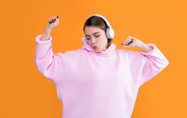 Mutlu genç kız sarı arka planda kulaklıkla müzik dinliyor..