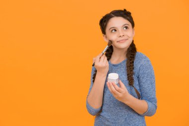 Stüdyoda makyaj yapan genç bir kızın fotoğrafı. Pudra fırçası kullanarak makyaj yapan güzel bir genç kız. Cilt bakımı. Sağlıklı bir cilde makyaj yapmak. Çocuk makyaj ürünleri. Boşluğu kopyala.