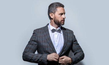 Stüdyoda erkek giyim. Erkek giyim kuşamının portresi. Erkekler smokin giyer, erkek giyer. Smokinli adam gri arka planda izole edilmiş..