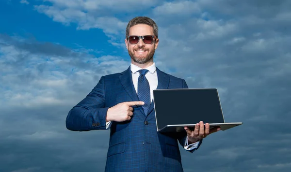 ノートパソコンのスーツを着てるビジネスマンだ ノートパソコンを提示するビジネスマンの写真 ノートパソコンを空の背景に提示するビジネスマン ノートパソコンの屋外で — ストック写真