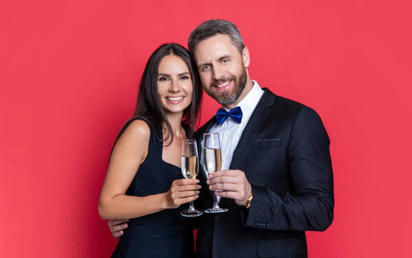 photo of lovely couple cheering and celebrate with champagne. couple cheering and celebrate isolated on red. couple cheering and celebrate in studio. couple cheering and celebrate on background.