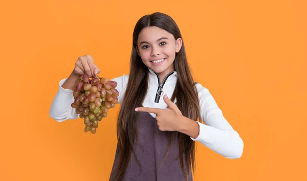 Stock image happy child holding fresh grapes fruit on yellow background.